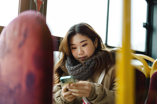 Young woman traveling by bus and using smart phone