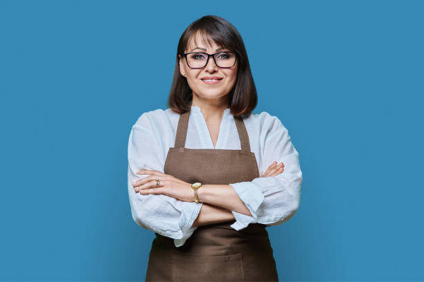 istock Confident middle aged woman in apron looking at camera on white background 1451391495