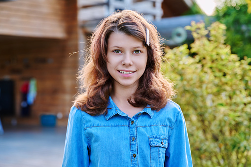 Portrait of a teenage girl 12, 13 years old outdoor, smiling girl looking at the camera