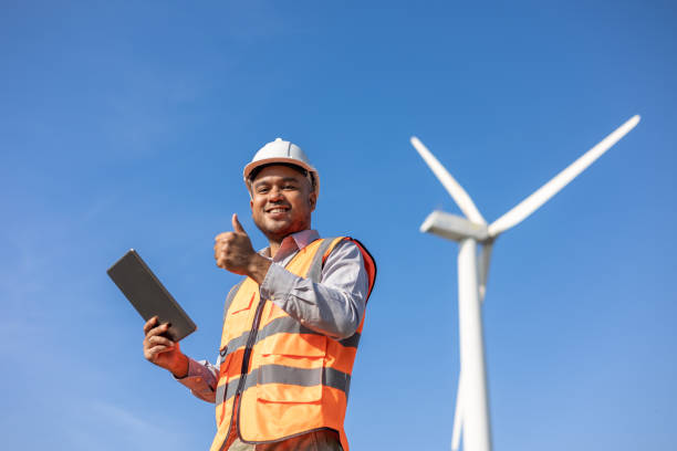 istock Engineer India man working with tablet at windmill farm Generating electricity clean energy. Wind turbine farm generator by alternative green energy. Asian engineer checking control electric power 1451396824