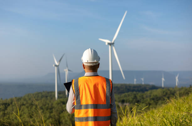 istock Engineer India man working with tablet at windmill farm Generating electricity clean energy. Wind turbine farm generator by alternative green energy. Asian engineer checking control electric power 1451398157
