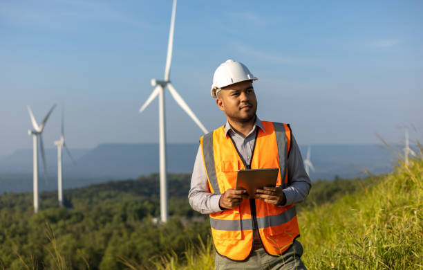 istock Engineer India man working with tablet at windmill farm Generating electricity clean energy. Wind turbine farm generator by alternative green energy. Asian engineer checking control electric power 1451398164