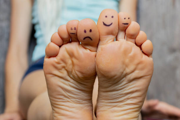 la alfombra en casa en el suelo pies descalzos de una niña con una sonrisa y tristeza dibujada a lápiz en los dedos, buen humor - clean feet fotografías e imágenes de stock