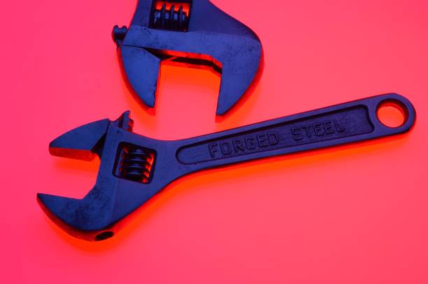 istock adjustable wrench and nuts of different sizes on a red background.Close-up. 1451405762