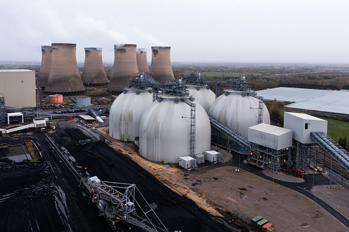 Large biofuel storage tanks or containers at a coal fired power station full of renewable biomass fuel to burn instead of coal ro reduce carbon footprint