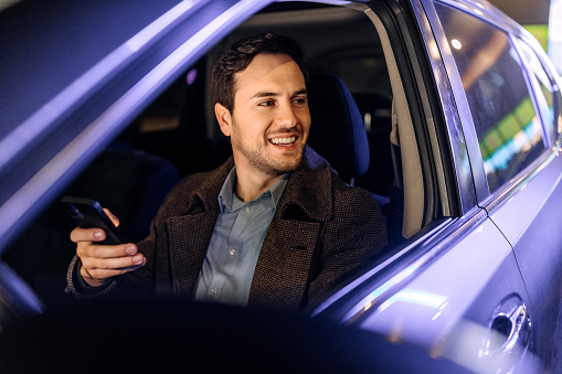 Well dressed young businessman text messaging from his car