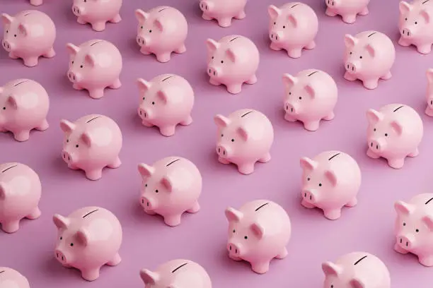 Photo of Array of pink piggy banks on pink background. Illustration of the concept of personal savings and financial investment
