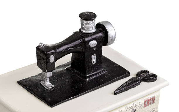 Vintage wooden box  for storing sewing supplies with miniature sewing machine,  a spool of thread and  three buds of rose. Close up. Copy space.