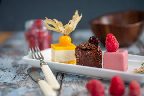 istock set of cakes, tangerine, chocolate and raspberry flavors, on a white rectangular plate, worn wooden background in blue tones. 1451424125