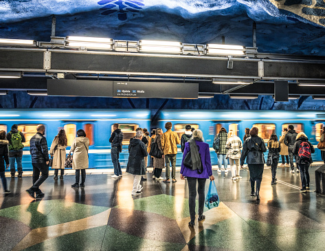 The subway station platform at T-Centralen in downtown Stockholm busy with passengers waiting as a train arrives in the station.