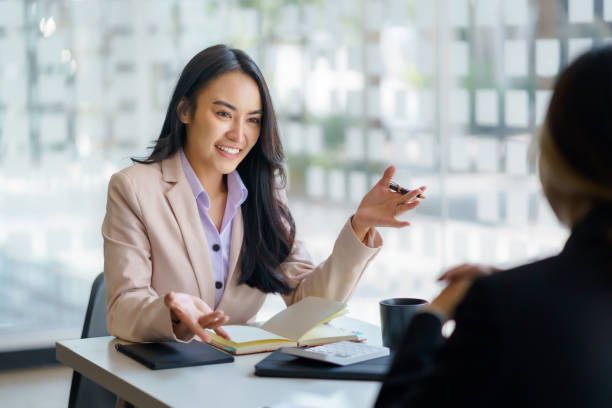Two young Asian businesswomen talk, consult, discuss working with new startup project idea presentation analyze plan marketing and investment in the office. stock photo