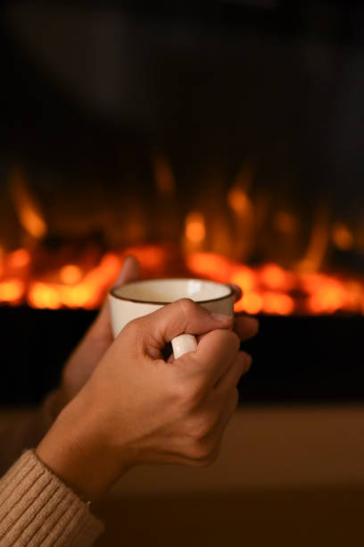 istock Hot chocolate in a mug on wooden table with cozy fireplace flame on the background 1451438482