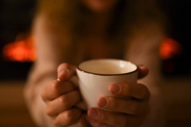 istock Hot chocolate in a mug on wooden table with cozy fireplace flame on the background 1451438539