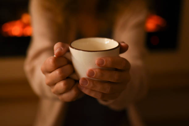 istock Hot chocolate in a mug on wooden table with cozy fireplace flame on the background 1451438585