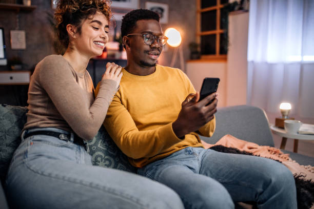 istock Young couple at home in the evening, having fun using smart phone 1451439756