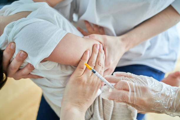 istock Infants being held by their mothers and receiving vaccinations 1451440576