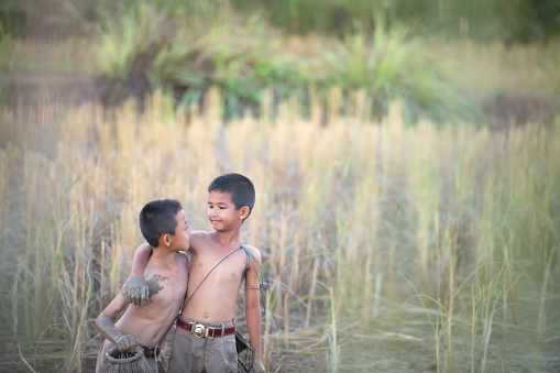 After class, little boys in rural Thailand like catching fish in the wetlands surrounding the rice fields to bring home to cook.