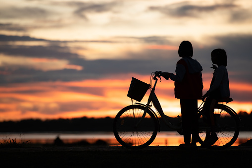 Little girls riding bicycles in the early morning light of the day while the sun beams a stunning shade of orange