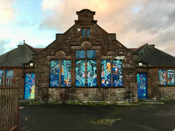 School is Most Certainly Out December 20th, 2022, Thornhill, Dumfries and Galloway, Scotland, UK.  An obsolete and derelict school sits off a main road, its windows and doors now covered with decorative murals to prevent damage and unwanted graffiti,   It has been replaced with a modern and shiny structure elsewhere in the town.

The old design features of a typical Victorian children's school, including the separate entrances for boys and girls, can be seen in this picture.

Though long abandoned, the ghosts of the children who played in its yards and learned in its classes, still seem to linger there. mcdermp stock pictures, royalty-free photos & images