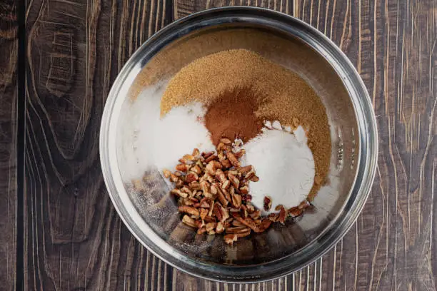 Sugar, pecans, and other ingredients in a mixing bowl viewed from above