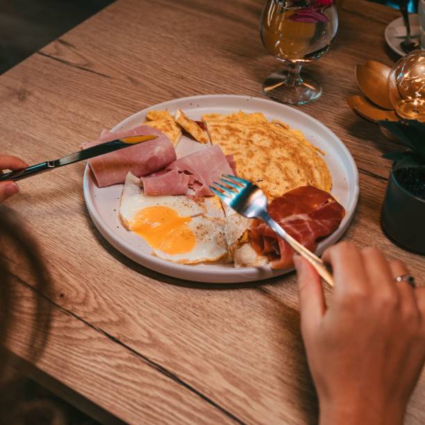 istock High-angle view of eggs, omelets, and hams served on a white plate 1451456713