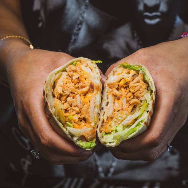 High-angle view of hands holding two fresh Mexican wraps