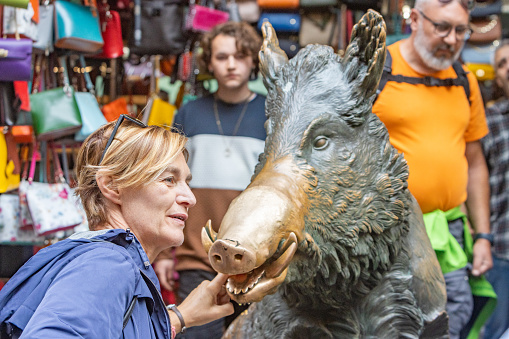 A woman places a coin in the mouth of the wild boar to ensure her return to Florence. Next she will rub the snout to guarantee good luck. That's why the snout has the striking white appearance - because it’s constantly rubbed by tourists. Il Porcellino (which means 'piglet' in Italian) is the name for this bronze fountain. It was designed by Pietro Tacca (1577-1640) in about 1634. The original; statue represents the Calydonian Boar of Greek myth. It's located at the Mercato Nuovo.