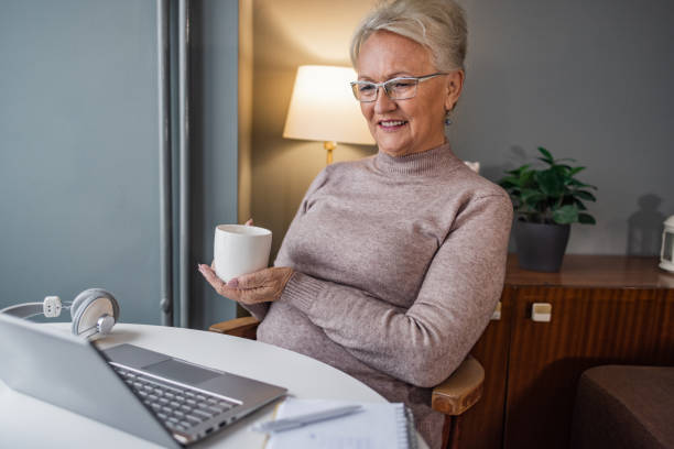 istock Senior woman drinking coffee and using laptop at home 1451466227