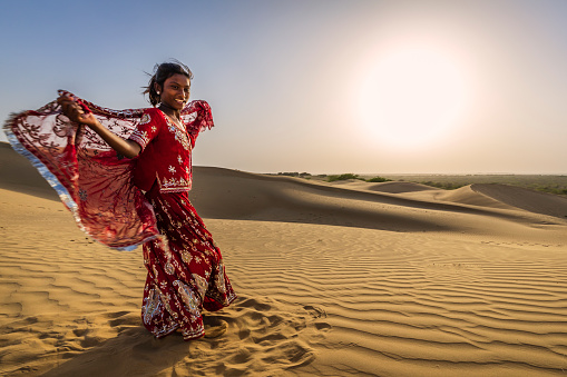 Young Indian girl dancing on a sand dune, Thar Desert, Rajasthan, India