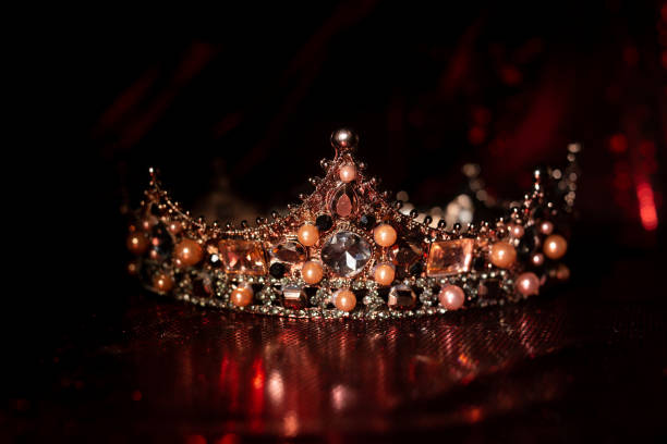istock Royal crown with precious gems on red luxury fabric background. King and queen 1451468942