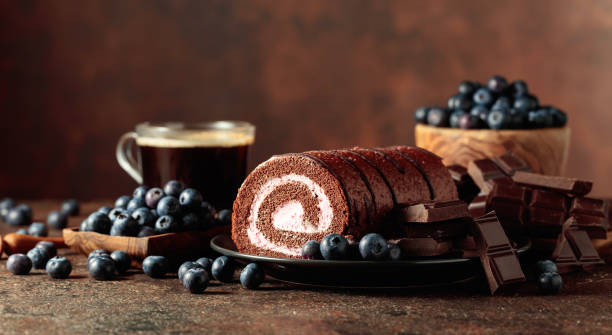 Chocolate roll cake with blueberries and a broken chocolate bar.