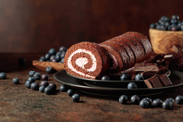 Chocolate roll cake with blueberries and a broken chocolate bar.