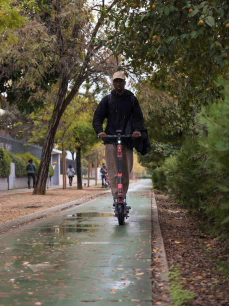 giovane uomo afroamericano su uno scooter elettrico a noleggio. giovane su uno scooter elettrico nella pista ciclabile. trasporti alla moda non inquinanti. - nonpolluting foto e immagini stock