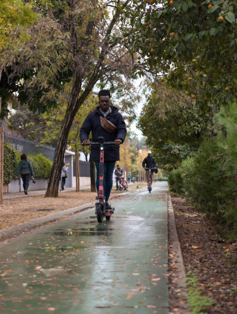 giovane uomo afroamericano su uno scooter elettrico a noleggio. giovane su uno scooter elettrico nella pista ciclabile. trasporti alla moda non inquinanti. - nonpolluting foto e immagini stock