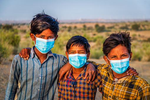Three Indian young boys wearing face masks - desert village, Thar Desert, Rajasthan, India.