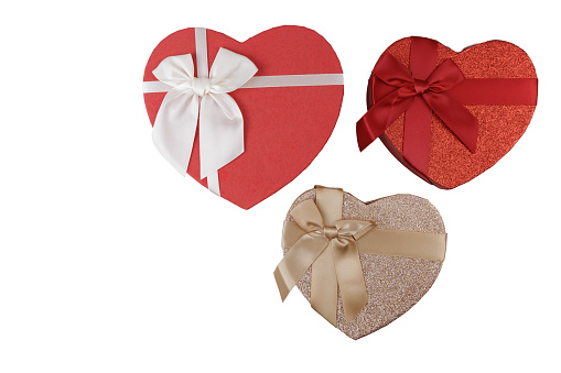 Red and gold different size heart shaped boxes with white, red and gold bows for Valentine's Day on a white background for gift