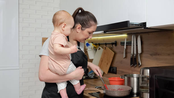 la bambina guarda la madre occupata che cucina il cibo in cucina - mother emotional stress exhaustion cooking foto e immagini stock