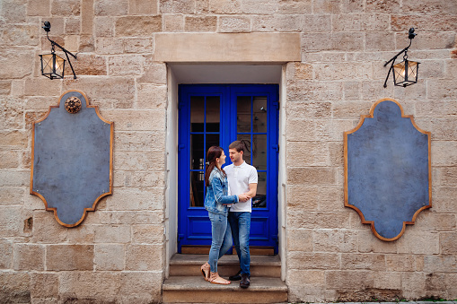 a beautiful brick wall and a chic blue door. a young couple standing next to doors