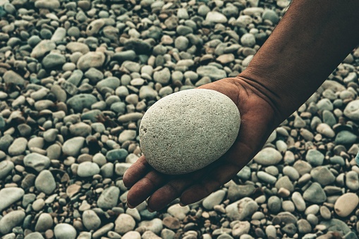 A closeup shot of a hand holding the sea pebble