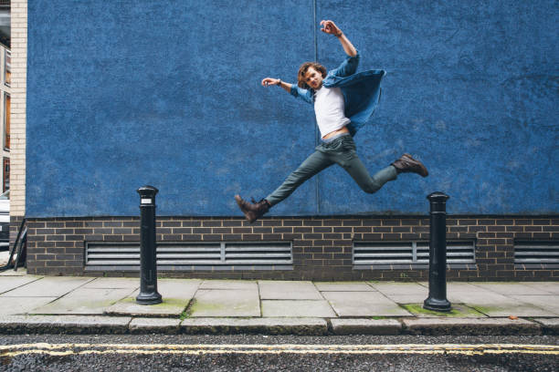 istock Young man in London jumping against a blue wall 1451485326