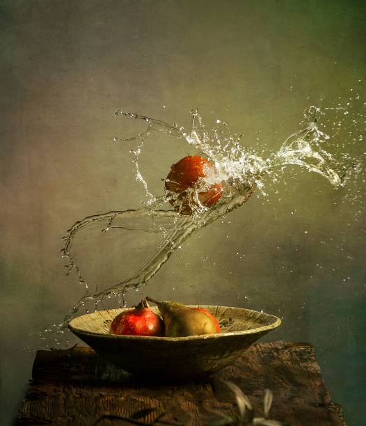 Photo still life with fruit, pomegranate, pear and falling apple from top with water splash