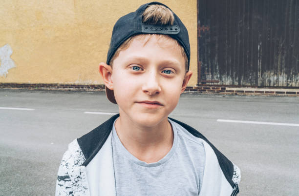 portrait de mode d’un caucasien aux yeux bleus aux cheveux blonds garçon adolescent skateboarder de 13 ans portant une casquette de baseball.  génération des jeunes temps libre consacré et image conceptuelle des personnes actives. - baseball cap baseballs male old photos et images de collection