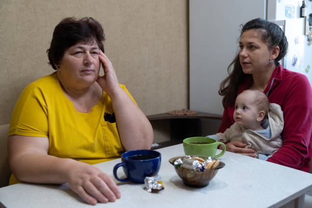 istock The woman experiences a headache while drinking tea with her family. 1451491195