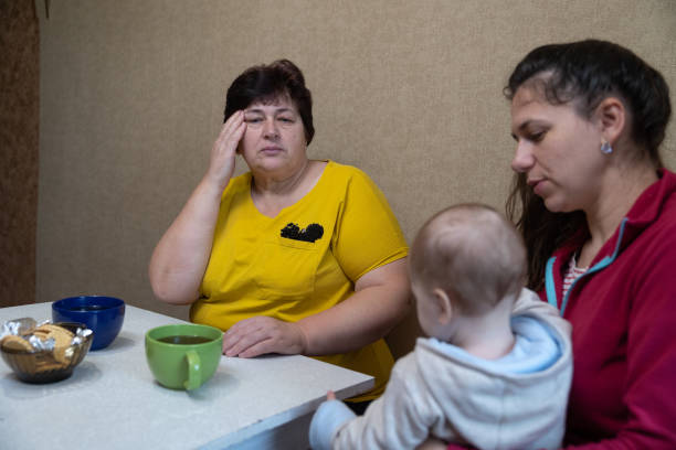 The woman experiences a headache while drinking tea with her family.