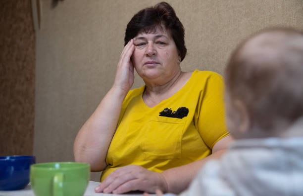 istock The woman experiences a headache while drinking tea with her family. 1451491282