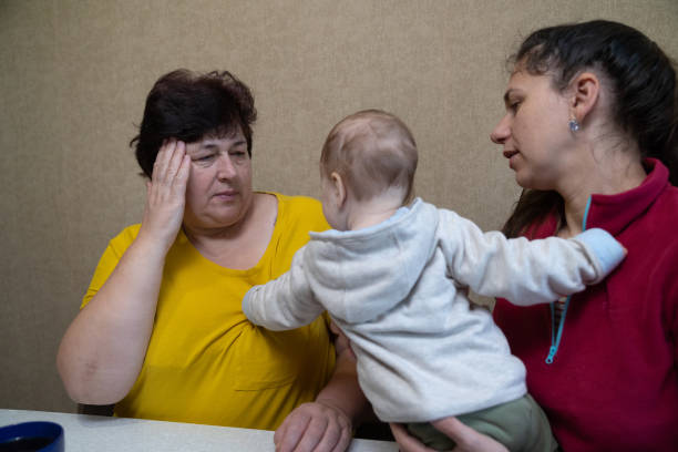 The woman experiences a headache while drinking tea with her family.