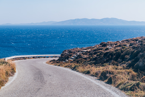 Winding roads of Tinos Island with crystal clear water of the Aegean Sea on Tinos island, Cyclades, Greece
