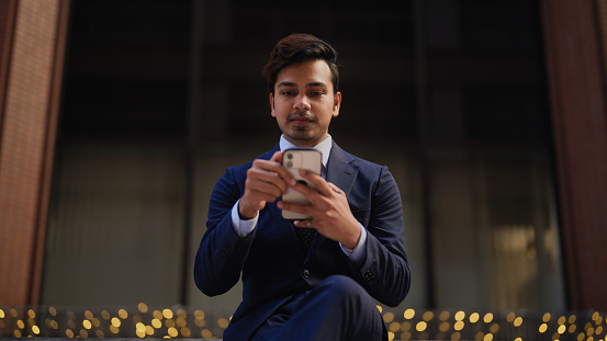 A handsome businessman is using a smart phone in city.