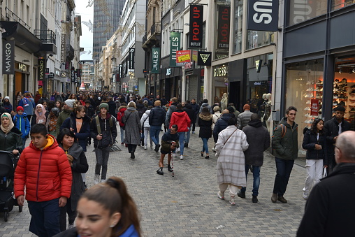 Brussels, Belgium - December 22, 2022: shoppers at noon in the city street Nieuwstraat, Rue Neuve, New street during daytime working day before Christmas time