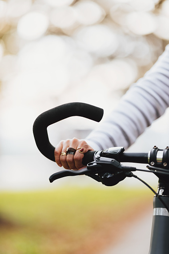 Zoomed in photo of woman's hand holding a bicycle handle while being outdoors.